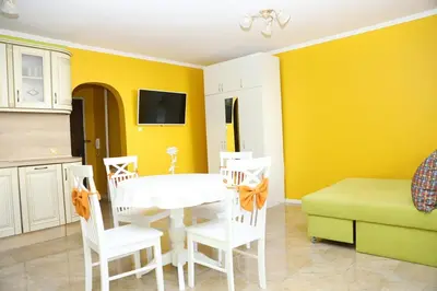a dining room with yellow walls and a white table and chairs at Flora Deluxe Studio in Burgas City