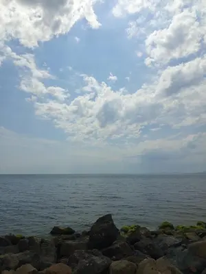 a large body of water with rocks and a cloudy sky at Ваканционен Апартамент in Aheloy