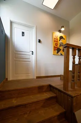 a hallway with a white door and wooden stairs at Tsaribrod Design Apartments in Varna City