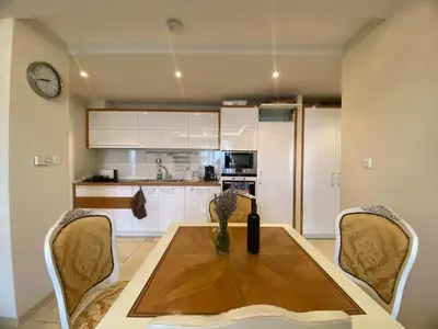 a kitchen with a table and chairs and a clock at Robinzon Beach 3BD Lux apartment by Flat Mаnager in Elenite