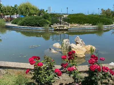 a pond in a park with red flowers at Зора-Обзор in Obzor