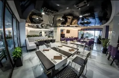 a dining room with tables and chairs and purple chairs at Апартамент в отеле Premier Fort Beach in Sveti Vlas