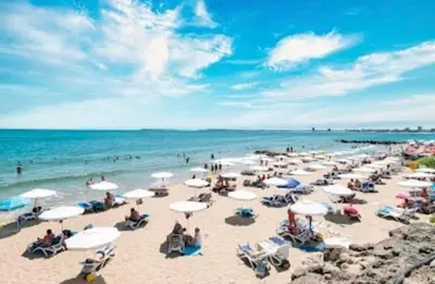 a group of people on a beach with umbrellas at Апартамент в отеле Premier Fort Beach in Sveti Vlas