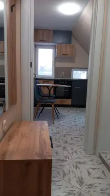 a room with a table and a desk and a window at Апартамент Плажен рай in Burgas City