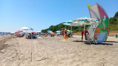 a group of people on a beach with umbrellas at Апартамент Плажен рай in Burgas City