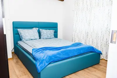 a blue bed with a blue headboard in a room at Апартамент Морски уют in Burgas City