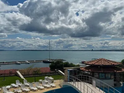 a group of chairs and a dock with a boat in the water at Diamond by the Sea in Sveti Vlas