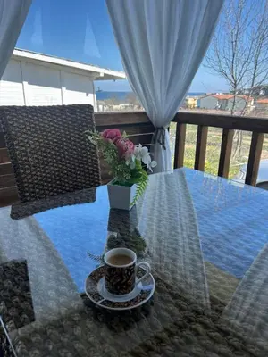 a cup of coffee and a vase of flowers on a table at Каравана Кътче от Рая in Tsarevo
