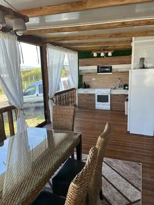 a living room with a table and chairs and a kitchen at Каравана Кътче от Рая in Tsarevo