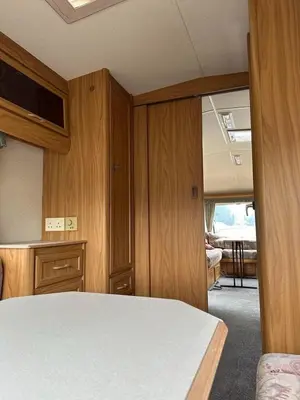 a room with a bed and wooden cabinets and a table at Каравана Кътче от Рая in Tsarevo