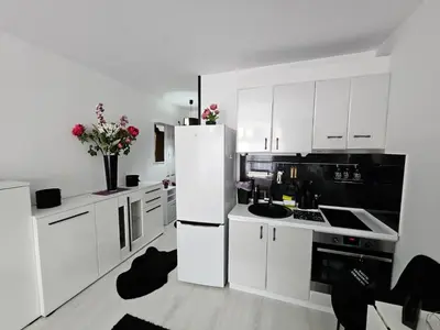 a white kitchen with black appliances and white cabinets at Romantic Sensual Retreat Studio by Flat Mаnager in Ravda