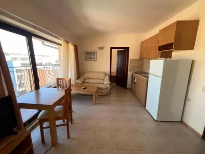 a kitchen with a refrigerator and a table and a couch at Rose Village Apartment in Sunny Beach