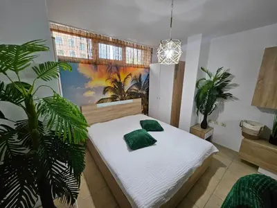 a bedroom with a bed with green pillows and a plant at Tropical Chic for Two, Basement Studio Escape by Flat Mаnager in Ravda