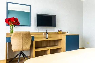 a room with a desk with a television and a vase of flowers at Hotel Laguna SPA in Sveti Vlas