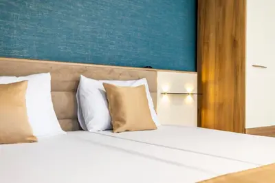 a bed with white pillows and a blue wall at Hotel Laguna SPA in Sveti Vlas