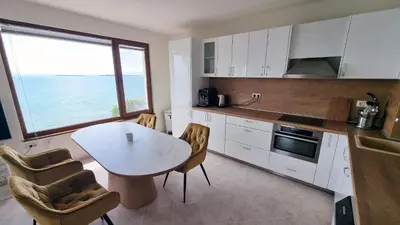 a kitchen with a table and chairs and a large window at Под наем 4-стаен Апартамент с Изумителна фронтална гледка море, Sun Coast resort Свети Влас in Sveti Vlas