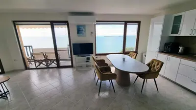 a kitchen with a table and chairs with a view of the ocean at Под наем 4-стаен Апартамент с Изумителна фронтална гледка море, Sun Coast resort Свети Влас in Sveti Vlas