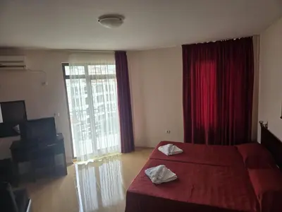 a hotel room with a red bed and a large window at Blue sky apartments in Sunny Beach