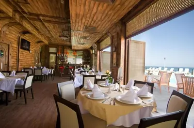 a restaurant with white tables and chairs and a large window at Appart complex - Egrek 4 in Lozenets