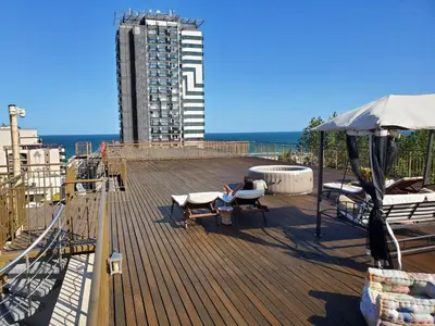 a person sitting on the deck of a building at Sea View Luxury Penthouse in Sunny Beach