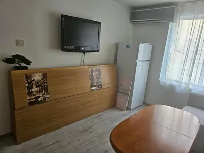 a living room with a television and a table at Малко студио в центъра на град Бургас II in Burgas City