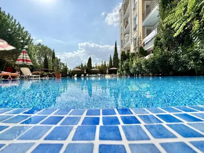 a swimming pool with a blue tile floor and a building at Messembria Palace - Menada Apartments in Sunny Beach
