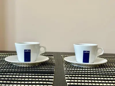 two coffee cups sitting on plates on a table at Messembria Palace - Menada Apartments in Sunny Beach