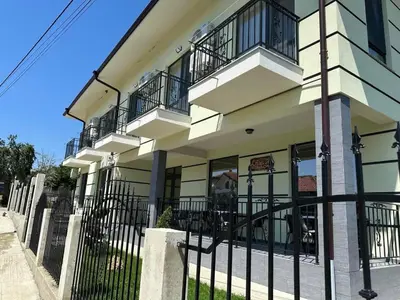 a white building with balconies and a black fence at Къща за гости Силвия in Shkorpilovtsi