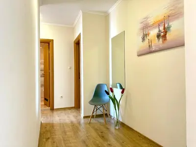 a hallway with a blue chair and a vase with flowers at Cosher - Gardenia Palace Apt 9 Free Parking in Pomorie