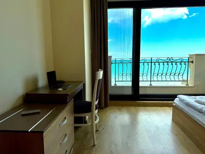 a hotel room with a desk and a bedroom with a window at Cosher - Gardenia Palace Apt 7 Free Parking in Pomorie