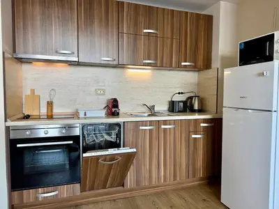 a kitchen with wooden cabinets and a white refrigerator at Cosher - Gardenia Palace Apt 11 Free Parking in Pomorie