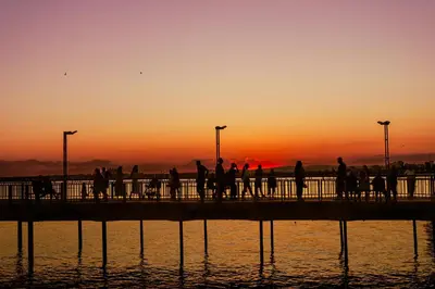 a group of people walking on a pier at sunset at Cosher - Gardenia Palace Apt 11 Free Parking in Pomorie