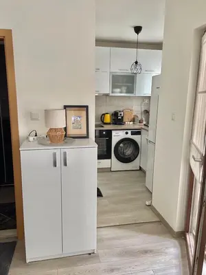 a kitchen with white cabinets and a washer and dryer at Deluxe studio beach Lazur in Burgas City