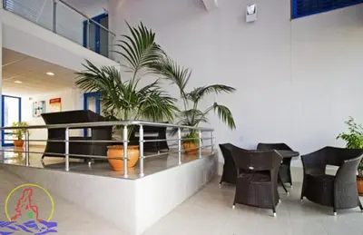 a lobby with chairs and plants in a building at Excelsior Prince ApartHotel in Sunny Beach