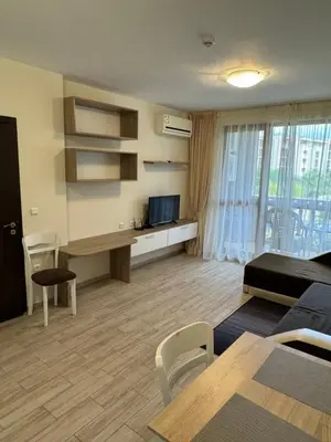 a living room with a couch and a table and a television at Апартамент Каскадас in Sunny Beach