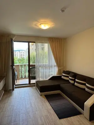 a living room with a couch and a large window at Апартамент Каскадас in Sunny Beach