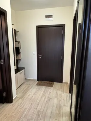 a hallway with a black door and a wooden floor at Апартамент Каскадас in Sunny Beach