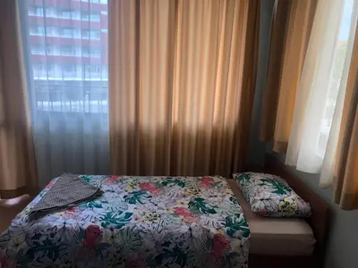 a bed in a bedroom with curtains and a window at Nesebar New Town Apartment in Nesebar