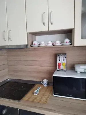 a kitchen with white cabinets and a counter top with a microwave at Comfort apartment near the beach in Varna City