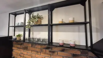 a black shelf with glasses on a brick wall at Cozy Corner in Varna - Free Parking in Varna City