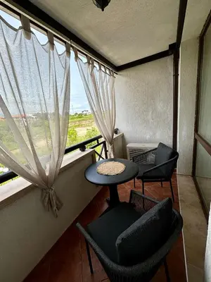 a balcony with chairs and a table and a window at Oasis Premium Studio in Lozenets