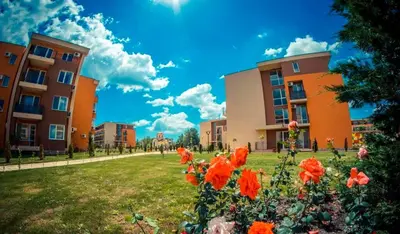 a group of buildings with red flowers in a park at 2 Bed Suite with Pool Views in Sunny Beach