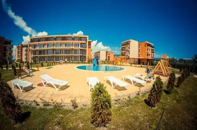 a group of chairs and a pool in front of a building at 2 Bed Suite with Pool Views in Sunny Beach
