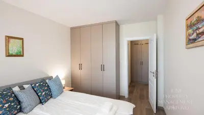 a white bedroom with a bed and a closet at Sea-breeze retreat Zerini in Burgas City