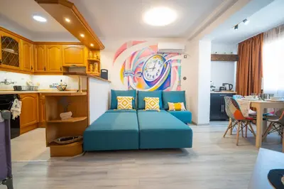 a living room with a blue couch and a clock on the wall at Бургаски вечери Burgas nights in Burgas City