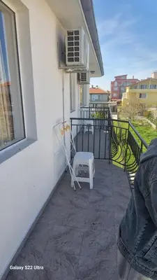 a balcony with a white chair and a window at Къща за гости Ravda in Ravda