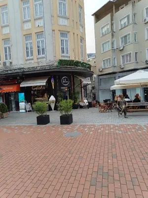 a city street with buildings and a plaza with potted plants at Апартамента на центъра на Варна до фонтаните in Varna City