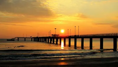 a pier with the sun setting over the ocean at Студио in Burgas City