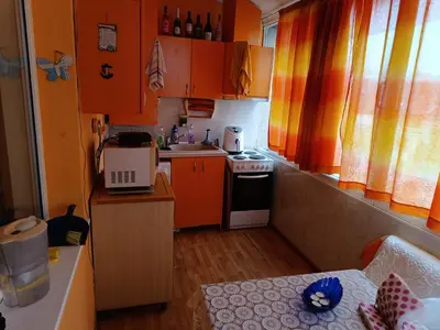 a small kitchen with orange cabinets and a stove at Апартамента на центъра на Варна до фонтаните и морето и градинта in Varna City