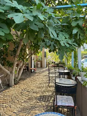 a patio with tables and chairs under a tree at Sveti Vlas, Rodopi Bay Apartment in Sveti Vlas